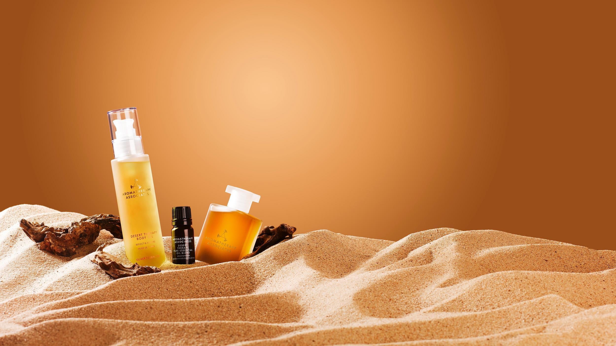 Aromatherapy Associates Desert Therapy collection on sand with a warm brown background