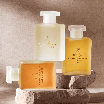 Three Aromatherapy Associates bottles on a stone surface with a neutral background