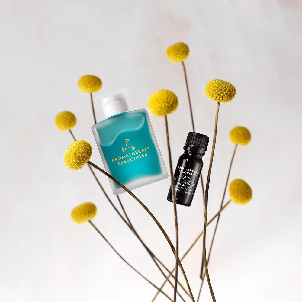 Two Aromatherapy Associates products on a white background with yellow flowers.