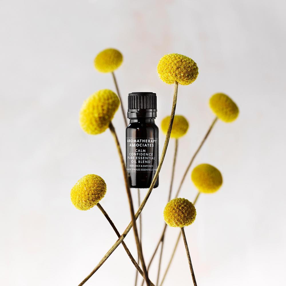 Black essential oil bottle with yellow flowers on a light gray background