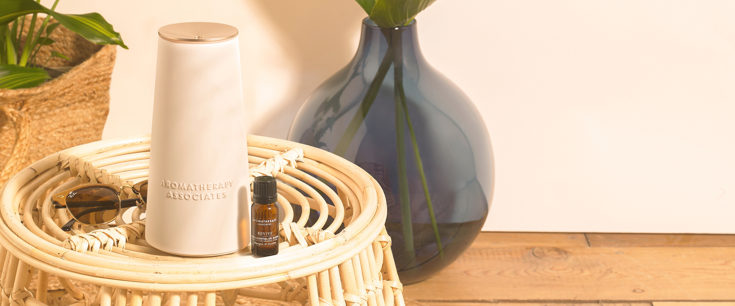 The Atomise, pure essential oil blend, and jewelry on a woven tray with a vase in the background.