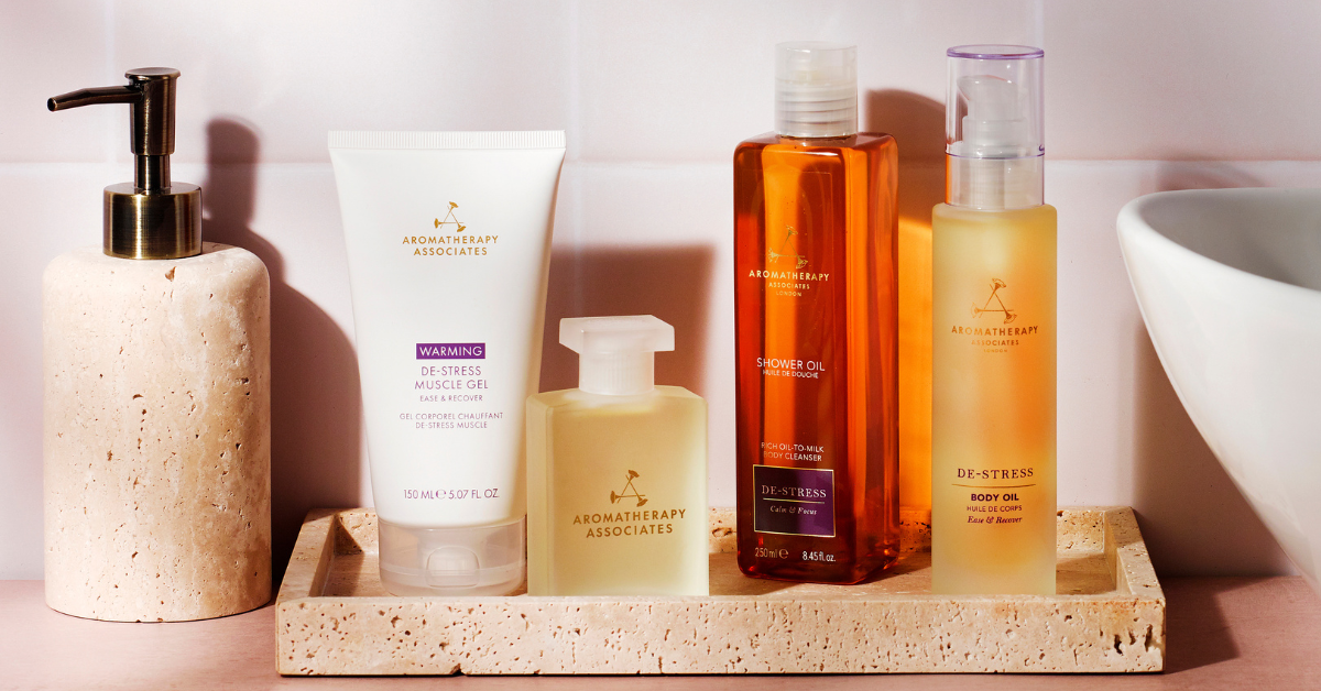 Collection of bath products including a pump bottle, tube, and bottles on a stone tray with a neutral background.