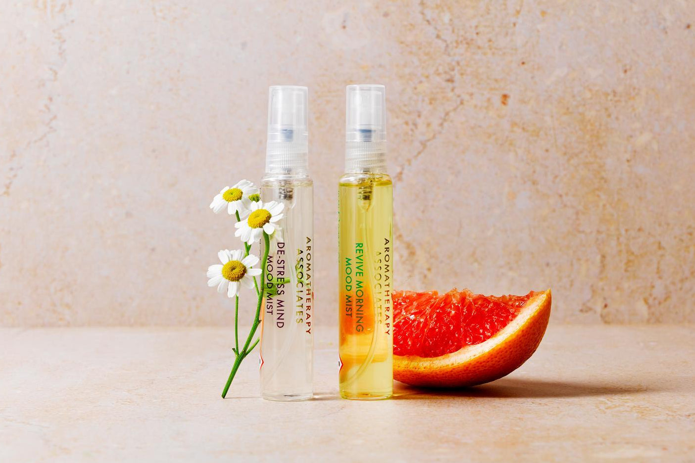 Two spray bottles with a slice of grapefruit on a beige surface