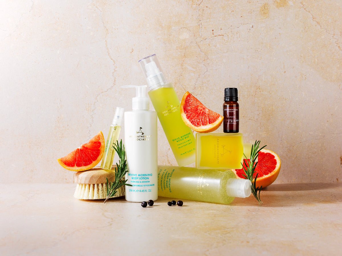 Collection of skincare products with grapefruit slices and a brush on a light background