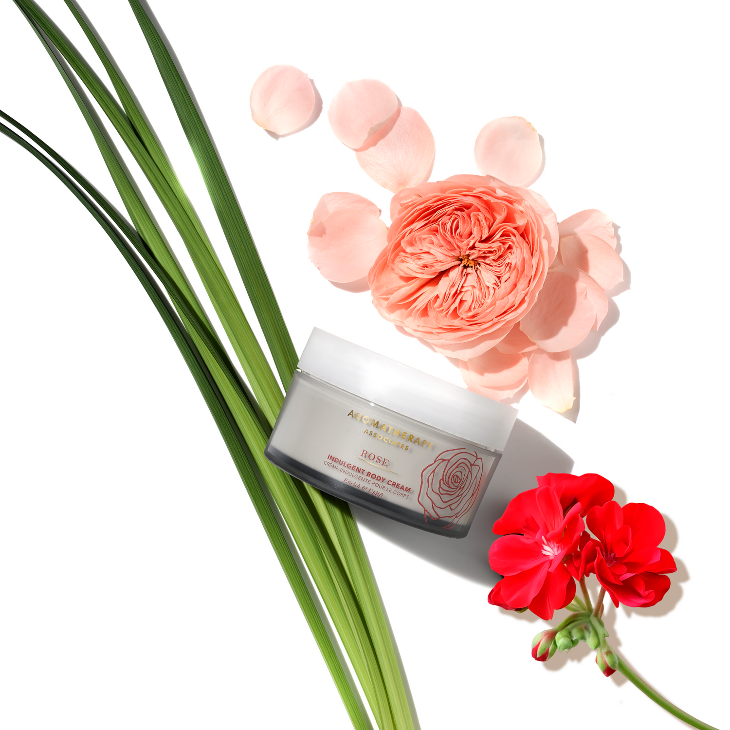 Jar of Aromatherapy Associates Rose Indulgent body cream with pink and red flowers on a white background