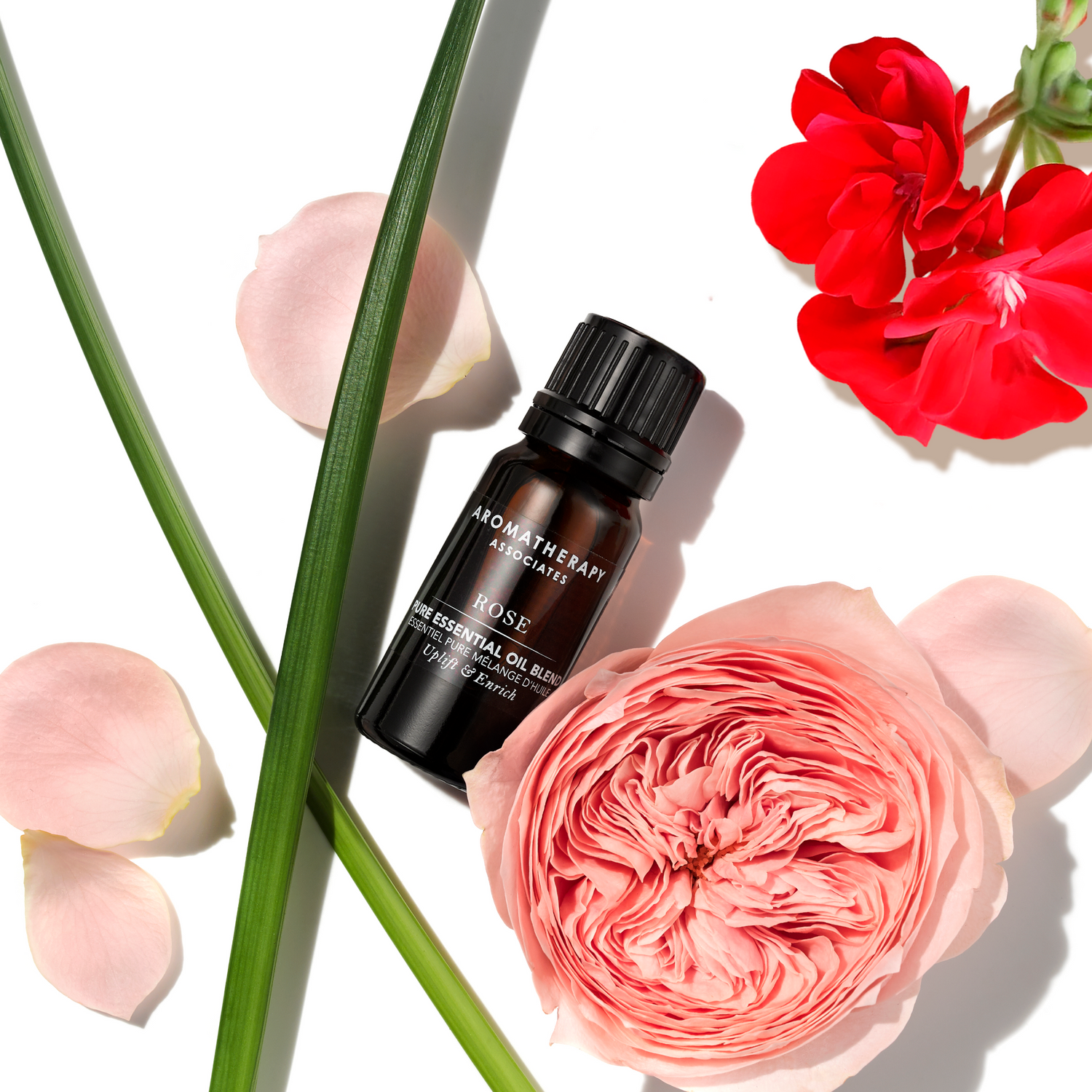 Aromatherapy Associates Rose essential oil bottle surrounded by flowers on a white background